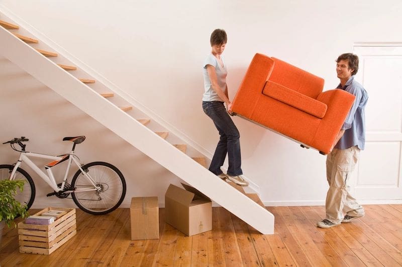 Woman and man carrying chair down the stairs to move